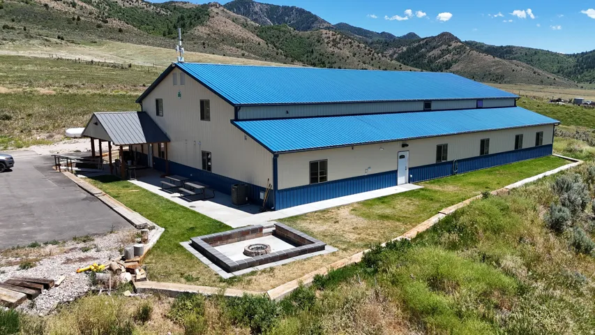 Large structure featuring a blue metal roof and siding, multiple windows, and a covered entry