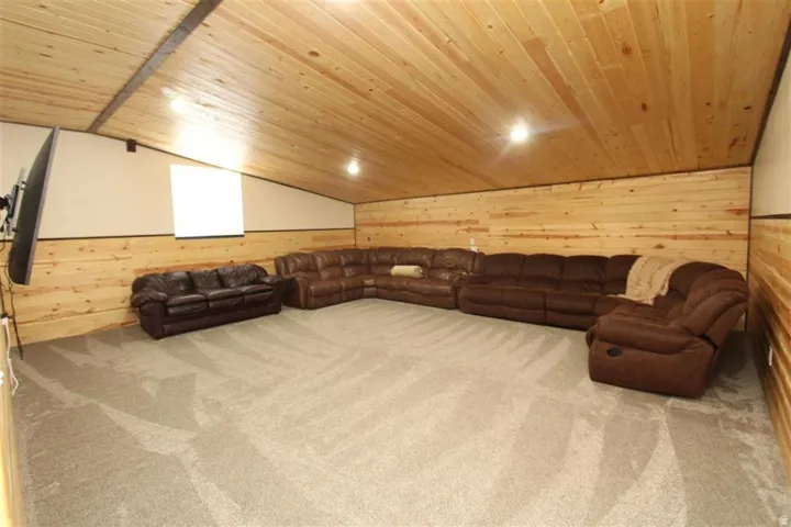 Spacious room featuring light wood-paneled walls and ceiling, a soft gray carpet, and recessed lighting