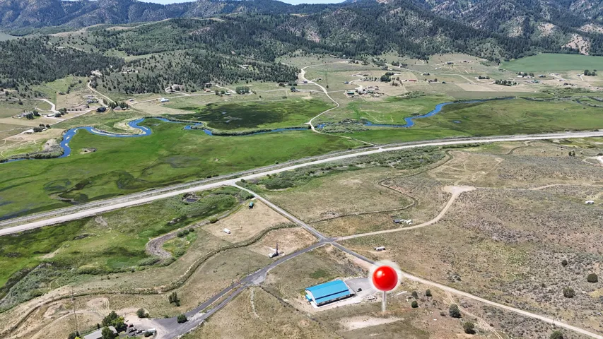 Expansive property featuring a blue-roofed building, surrounding roads, and distant mountains