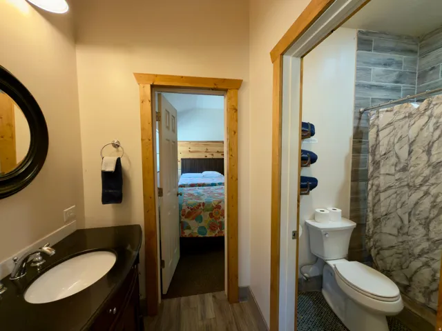 Bathroom featuring a dark wood-finish vanity with a dark countertop, an oval undermount sink, and a circular mirror