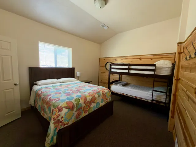 Bedroom featuring a vaulted ceiling, wood-finish accent wall, and carpet flooring