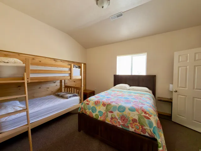Bedroom featuring a wooden bunk bed, a dark wood-finish bed frame, carpet flooring, a window, and a paneled white door