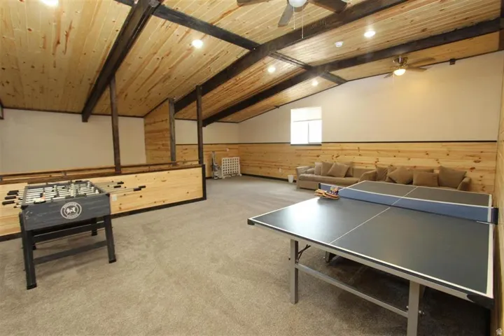 Spacious attic conversion featuring vaulted wood-paneled ceilings with exposed beams, recessed lighting, and ceiling fans