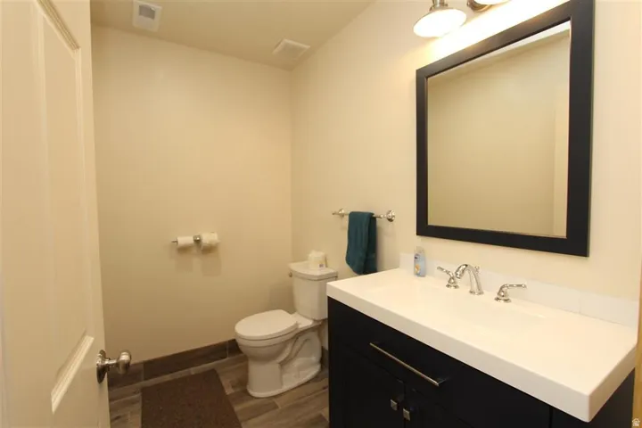 Bathroom featuring a dark wood-finish vanity with a white countertop and integrated sink, a framed mirror, and a two-light vanity fixture