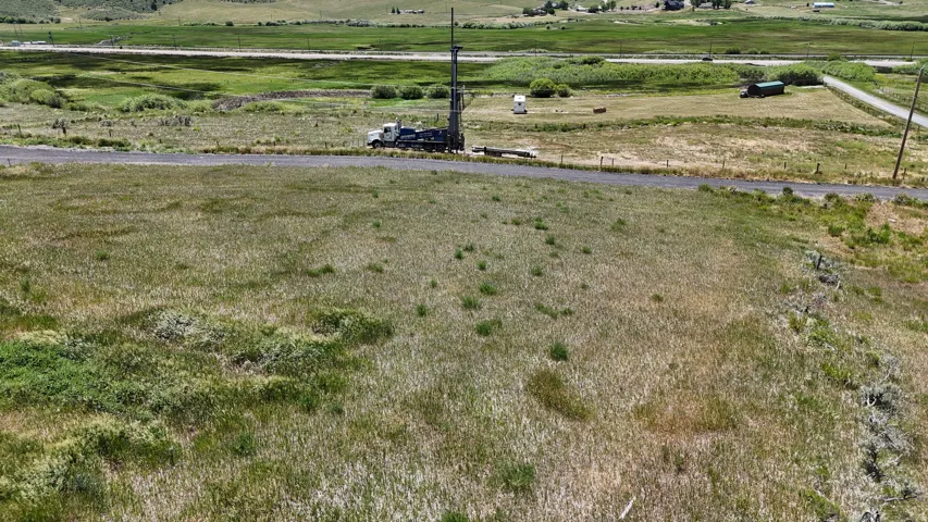 Expansive open land featuring natural grasses and distant green fields