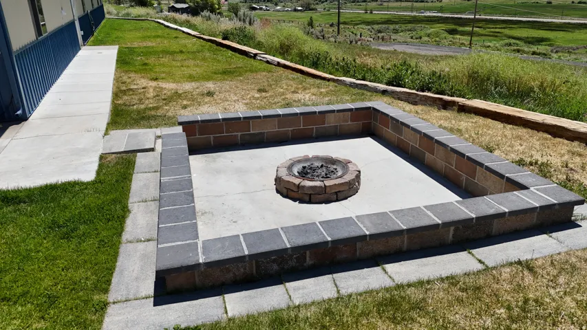 Outdoor fire pit with a brick and paver surround, set on a concrete pad