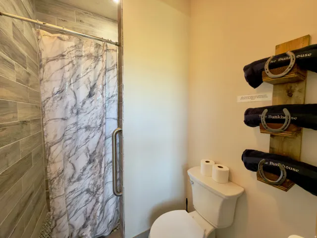 Shower area featuring vertical tile-finish walls and a curved grab bar