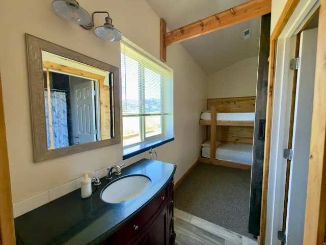 Bathroom vanity with integrated sink and dark countertop, complemented by a framed mirror and wall-mounted light fixture