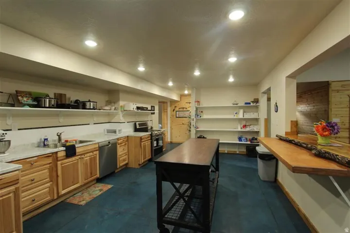 Spacious kitchen area featuring warm wood cabinetry, light-toned countertops, and a full suite of stainless steel appliances