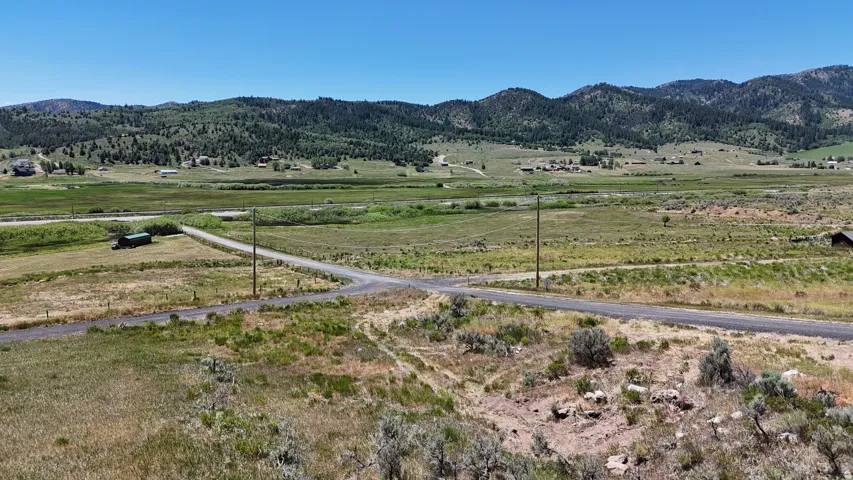 Expansive land parcel featuring a gravel road intersection and surrounding natural landscape