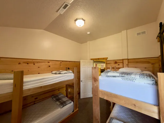 Room featuring wood-plank wainscoting, light-toned walls, and multiple wooden bunk beds