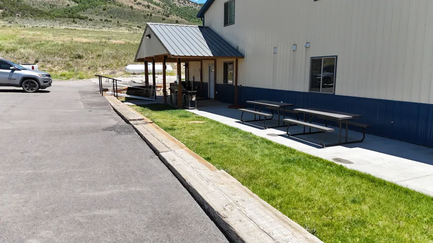 Paved parking area alongside a building with blue and white corrugated metal siding