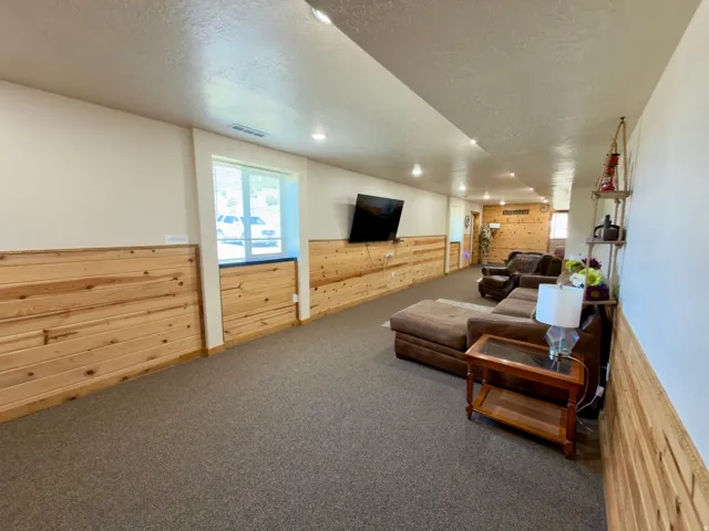 Spacious carpeted room featuring extensive horizontal wood paneling on lower walls