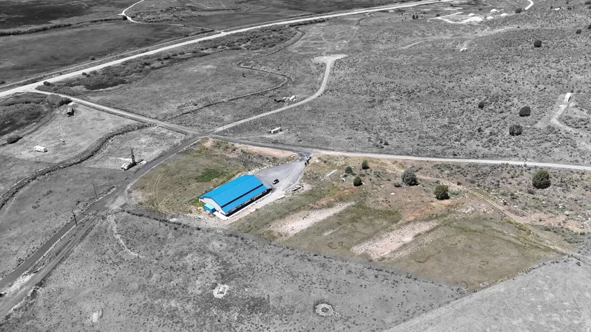 Commercial building with a blue metal roof and surrounding undeveloped land