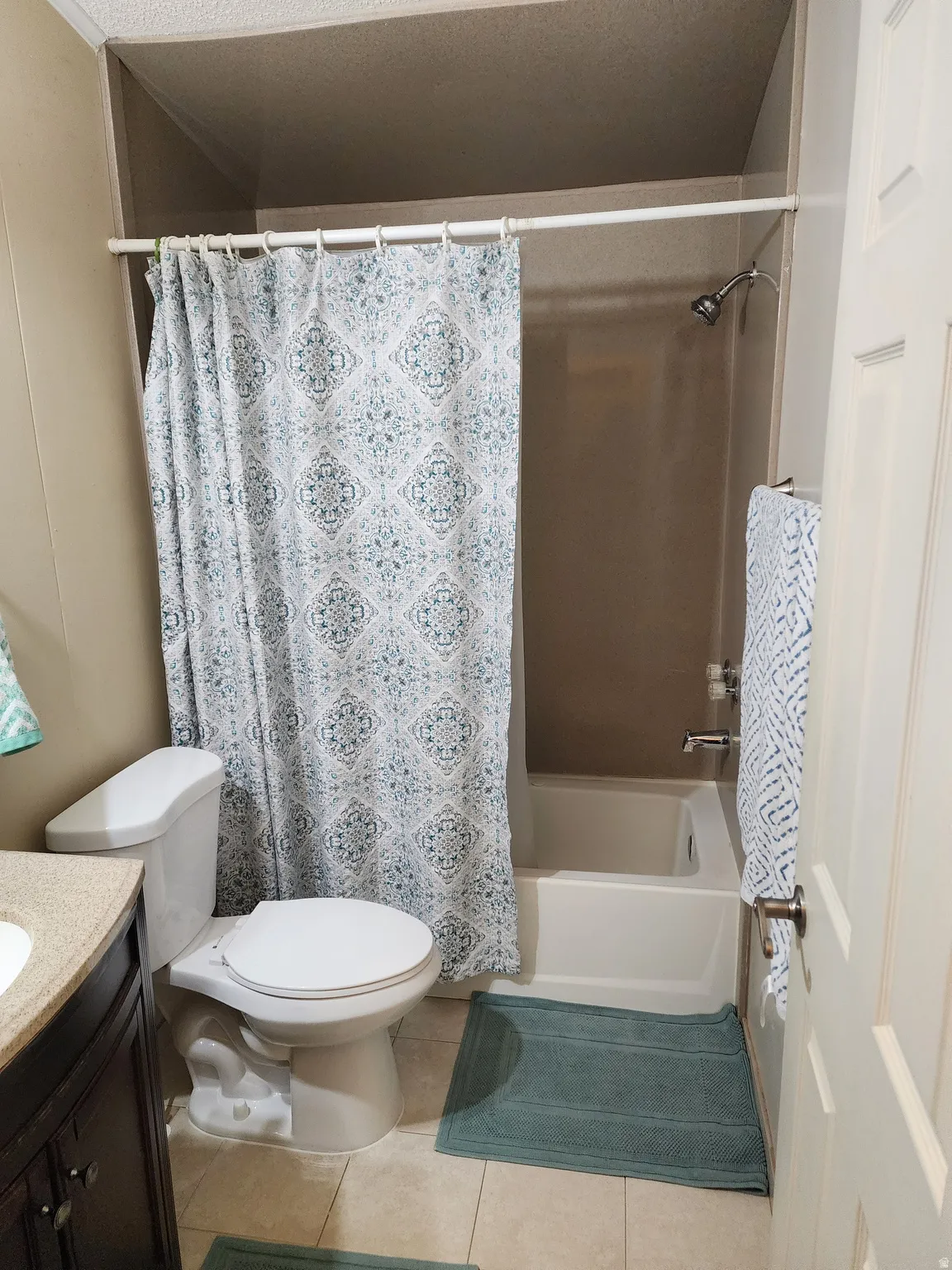 Full bath featuring a white toilet, a shower/tub combination, and a vanity with a dark wood-finish cabinet and a light-toned countertop