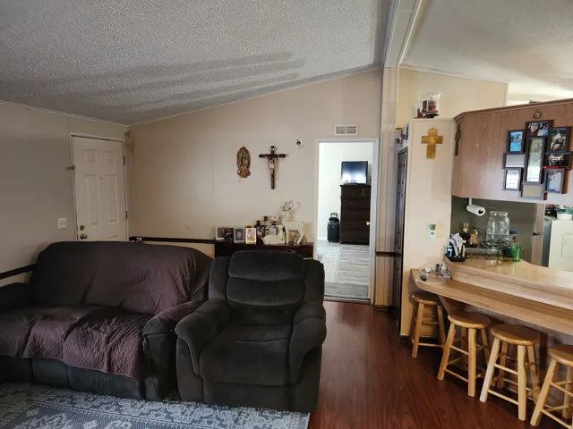 Open-concept living area featuring wood-finish flooring, a vaulted ceiling, and an integrated breakfast bar with a light wood countertop