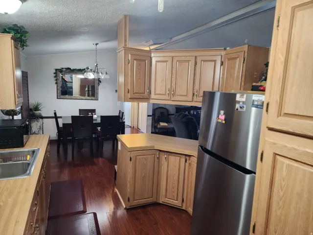 Kitchen featuring wood-finish flooring, light wood cabinetry, and a stainless steel refrigerator
