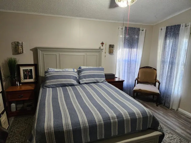 Bedroom featuring wood-finish flooring, light neutral wall paneling, and a contemporary ceiling fan with integrated lighting
