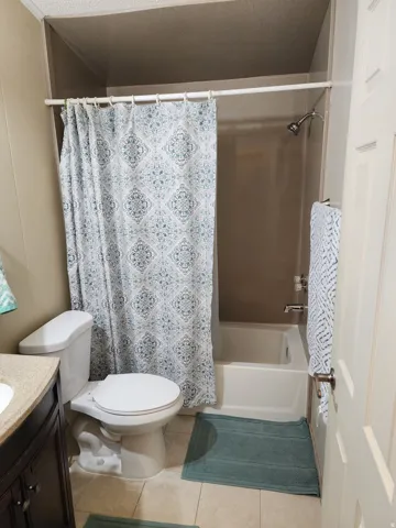 Full bath featuring a white toilet, a shower/tub combination, and a vanity with a dark wood-finish cabinet and a light-toned countertop