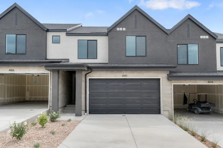 Contemporary townhome facade featuring a dark gray and light gray stucco exterior with dark-framed windows