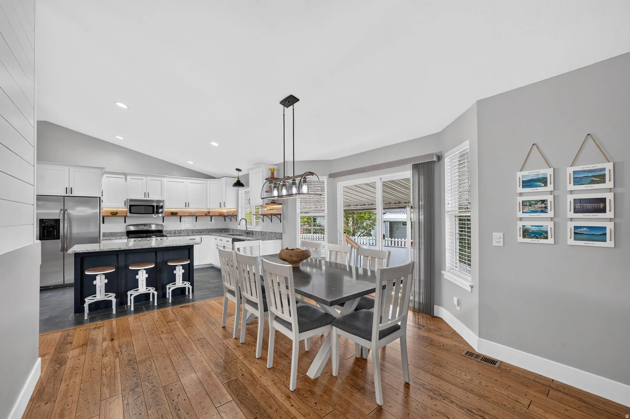 Open-concept dining area featuring wood-finish flooring, a contemporary chandelier, and a bay window