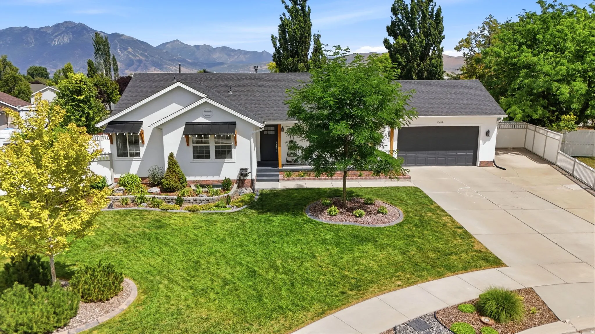 Ranch-style exterior with a dark shingle roof and white stucco siding