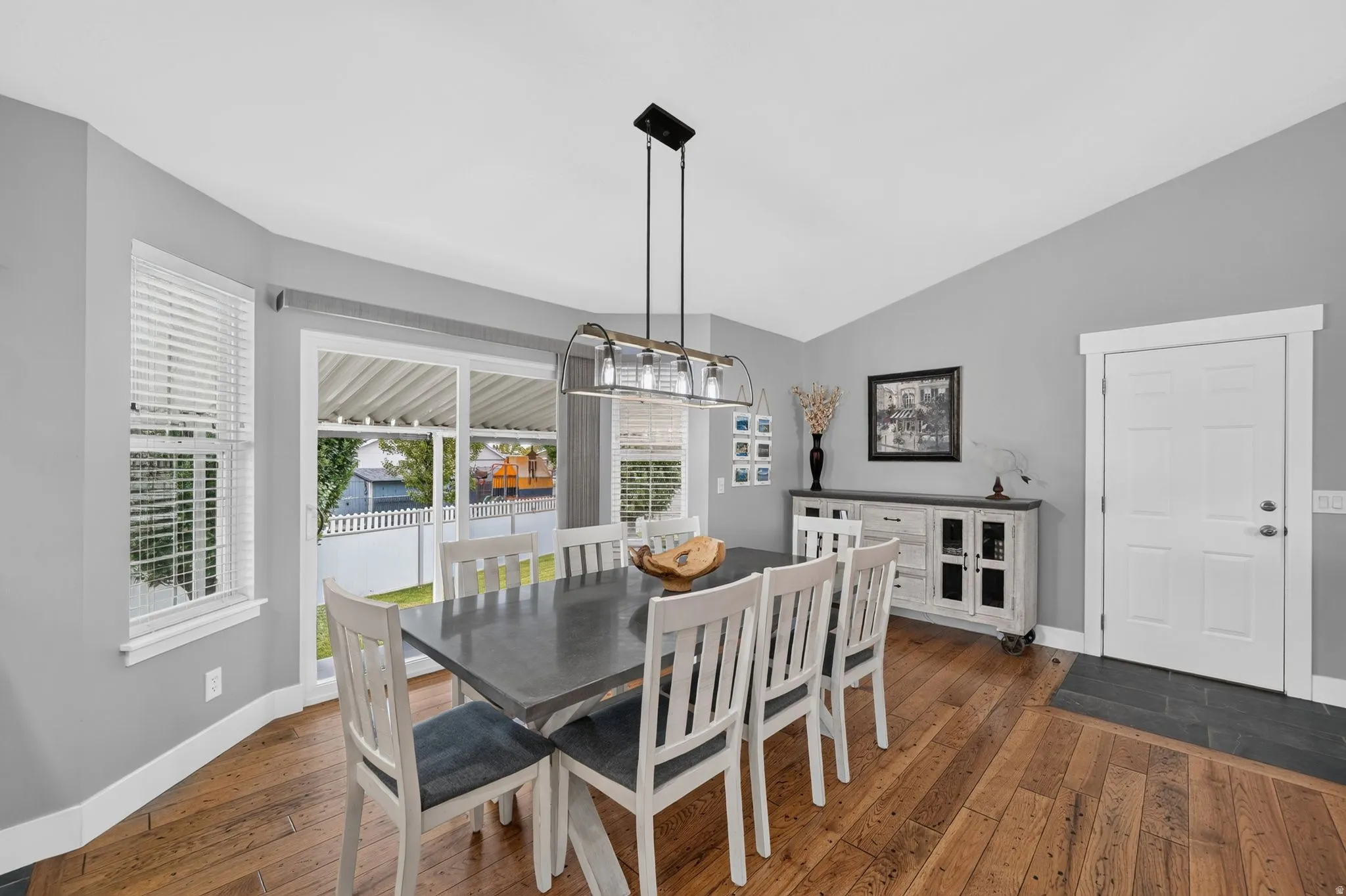 Dining area featuring hardwood flooring, a contemporary linear chandelier, and a sliding glass door providing access to the exterior