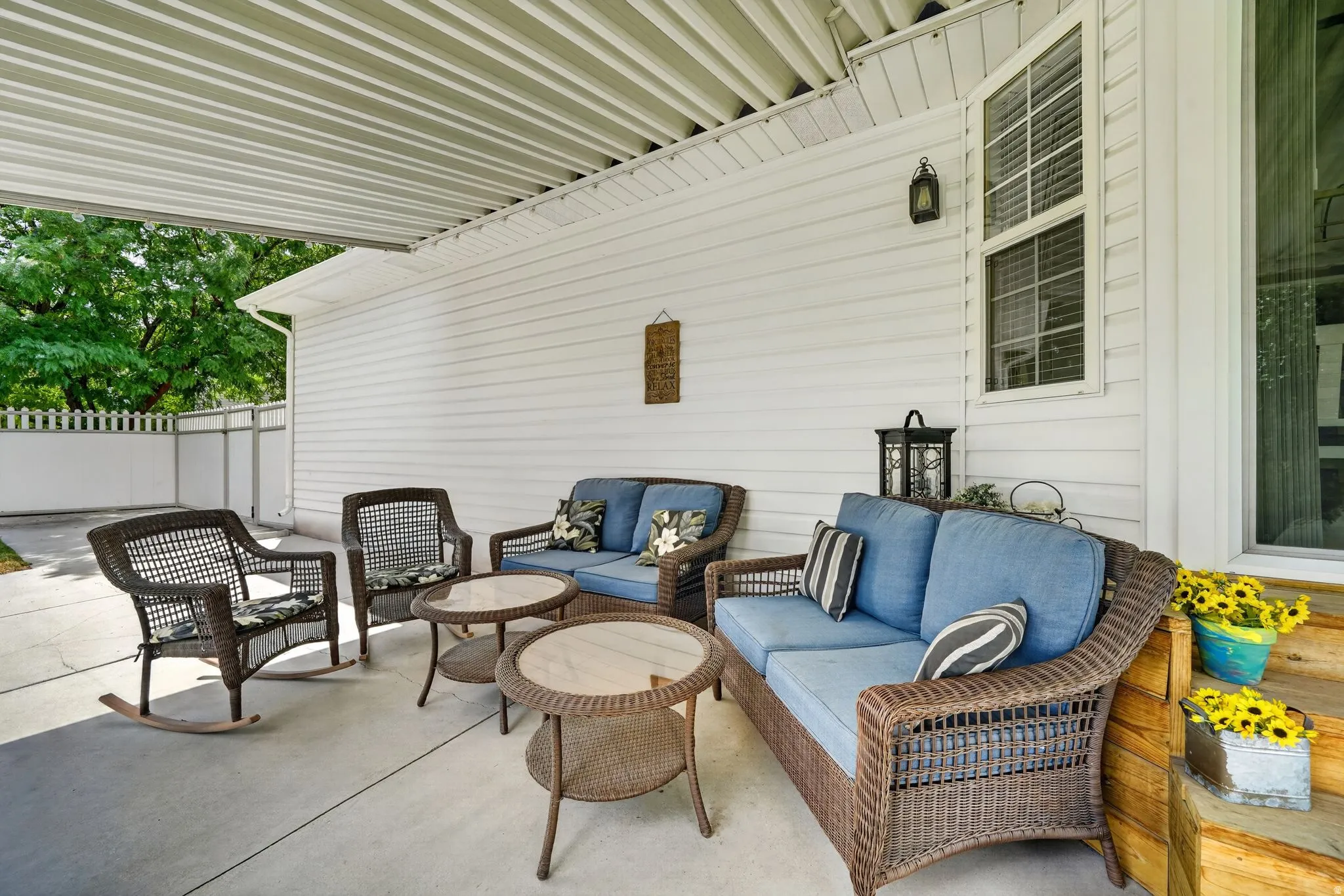 Poured concrete patio featuring a white slatted overhead cover and white vinyl siding