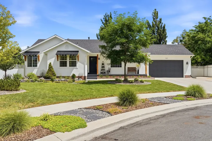 White stucco exterior featuring a dark asphalt shingle roof and a dark garage door