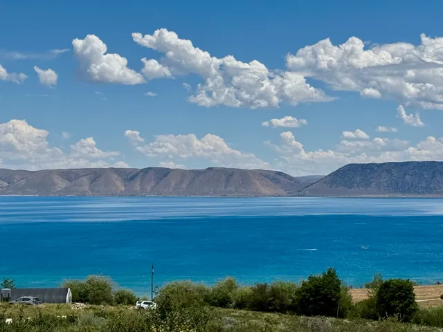Expansive water frontage with mountain backdrop, surrounded by natural vegetation