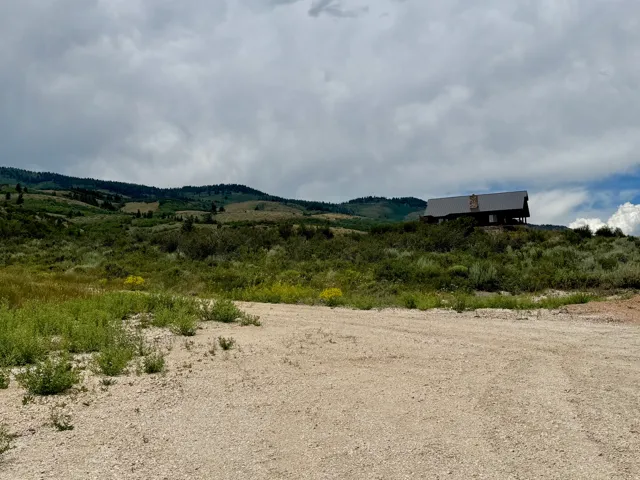 Hillside property featuring a cabin-style residence with a dark metal roof and stone chimney