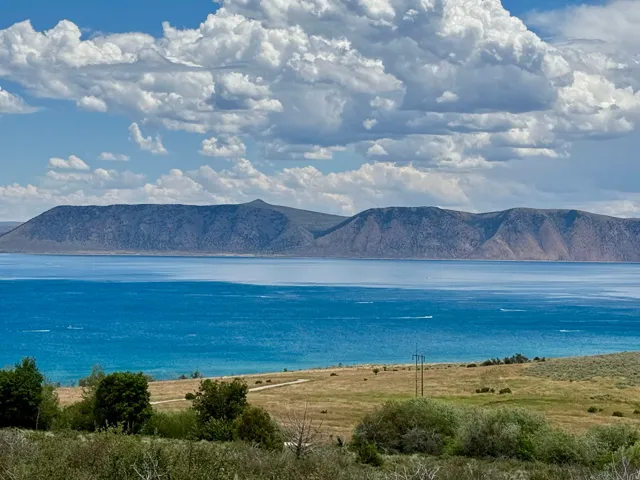 Expansive water body with distant mountain ranges under a sky with prominent clouds