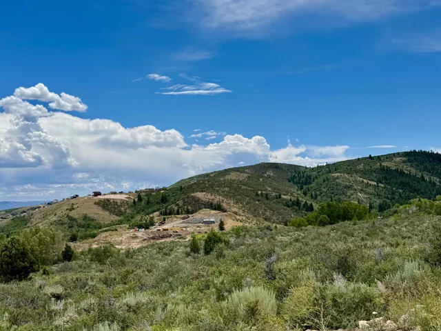 Expansive mountainous landscape featuring distant residential structures under construction