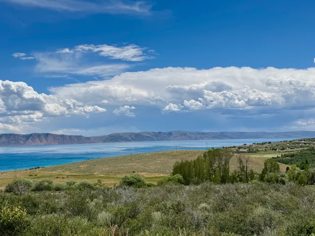 Expansive landscape featuring a large body of water, distant mountains, and varied natural terrain