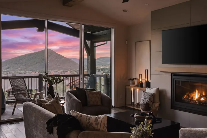 Expansive sliding glass doors opening to a covered balcony, featuring a mountain, golf course, and valley views, and outdoor seating
