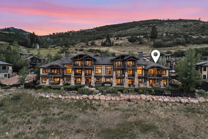Expansive multi-level structure featuring a stone and siding exterior, multiple balconies, and a distinctive peak roofline