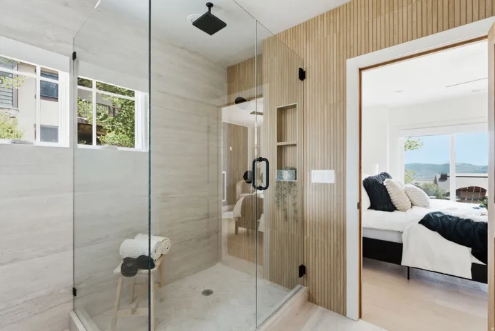 Spacious glass-enclosed shower featuring a rain showerhead, tiled walls, and a recessed niche
