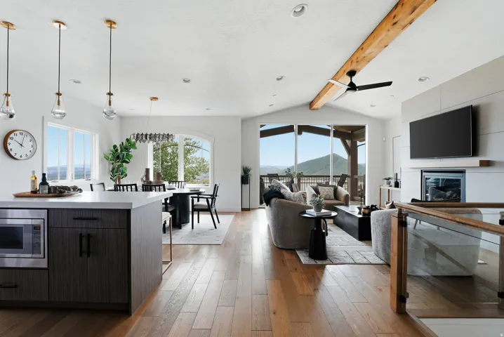 Open-concept living space featuring wood-finish flooring, a contemporary fireplace, and a vaulted ceiling with an exposed wood beam