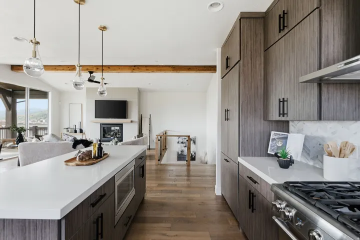 Open-concept kitchen and living area featuring a kitchen island, Calacatta marble backsplash, recessed microwave, and new pendant lighting