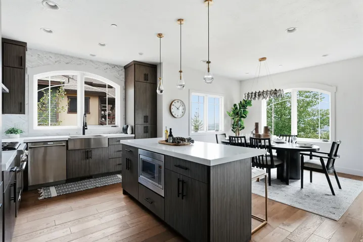 Contemporary kitchen featuring dark wood-finish cabinetry, stainless steel appliances, a center island with a built-in microwave, and light countertops
