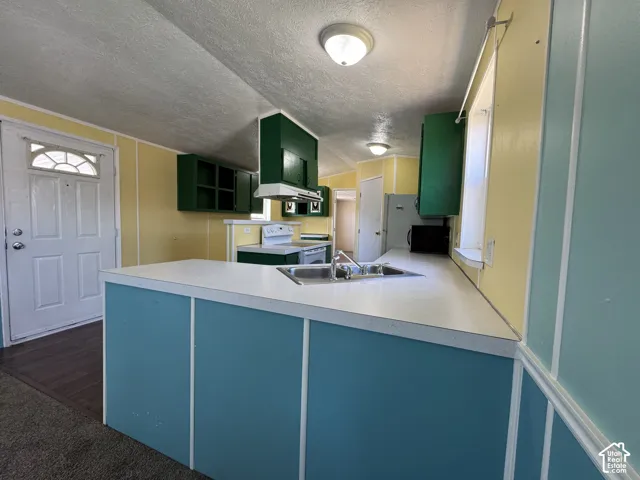 Kitchen featuring a double basin sink, white countertops, built-in cabinetry, and a range with an overhead microwave