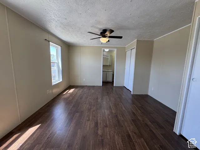 Spacious room featuring wood-finish flooring, a window providing natural light, and a ceiling fan with integrated lighting