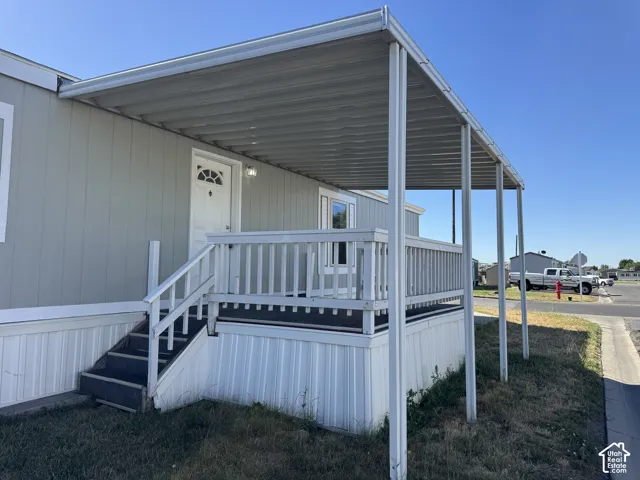 Front exterior featuring light gray siding, a covered porch with white railing, and white trim accents