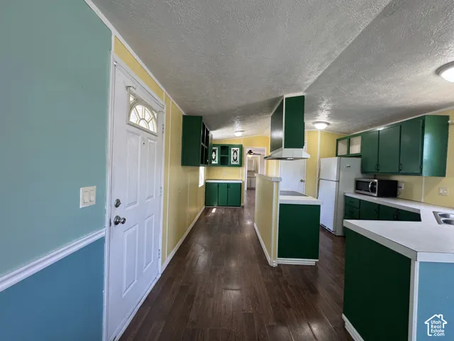 Kitchen featuring wood-finish flooring, green cabinetry, white countertops, and white appliances