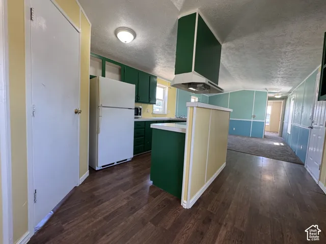 Kitchen featuring wood-finish flooring, green cabinetry, white appliances, and a white countertop