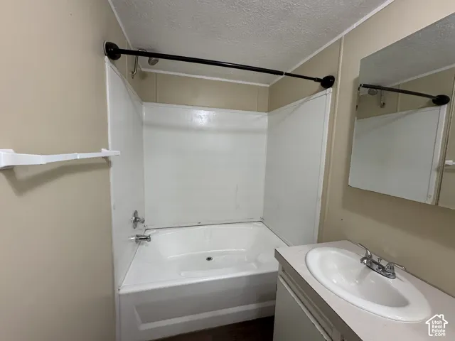 Bathroom featuring a white bathtub, shower surround, and a sink vanity with an integrated basin