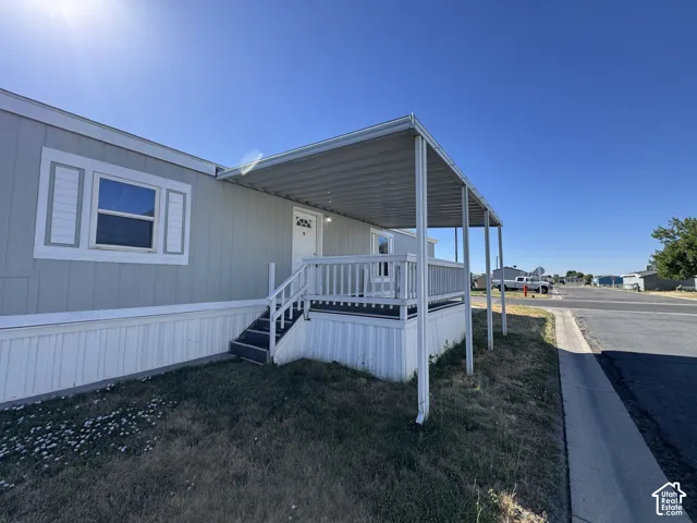 Light gray exterior siding with white trim, white front door, covered porch, white porch railing, and white window shutters