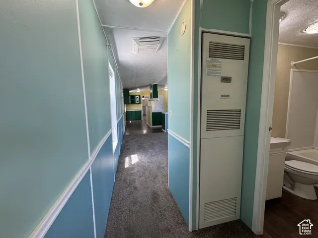 Hallway with two-tone paneling, gray carpet flooring, and a built-in utility closet