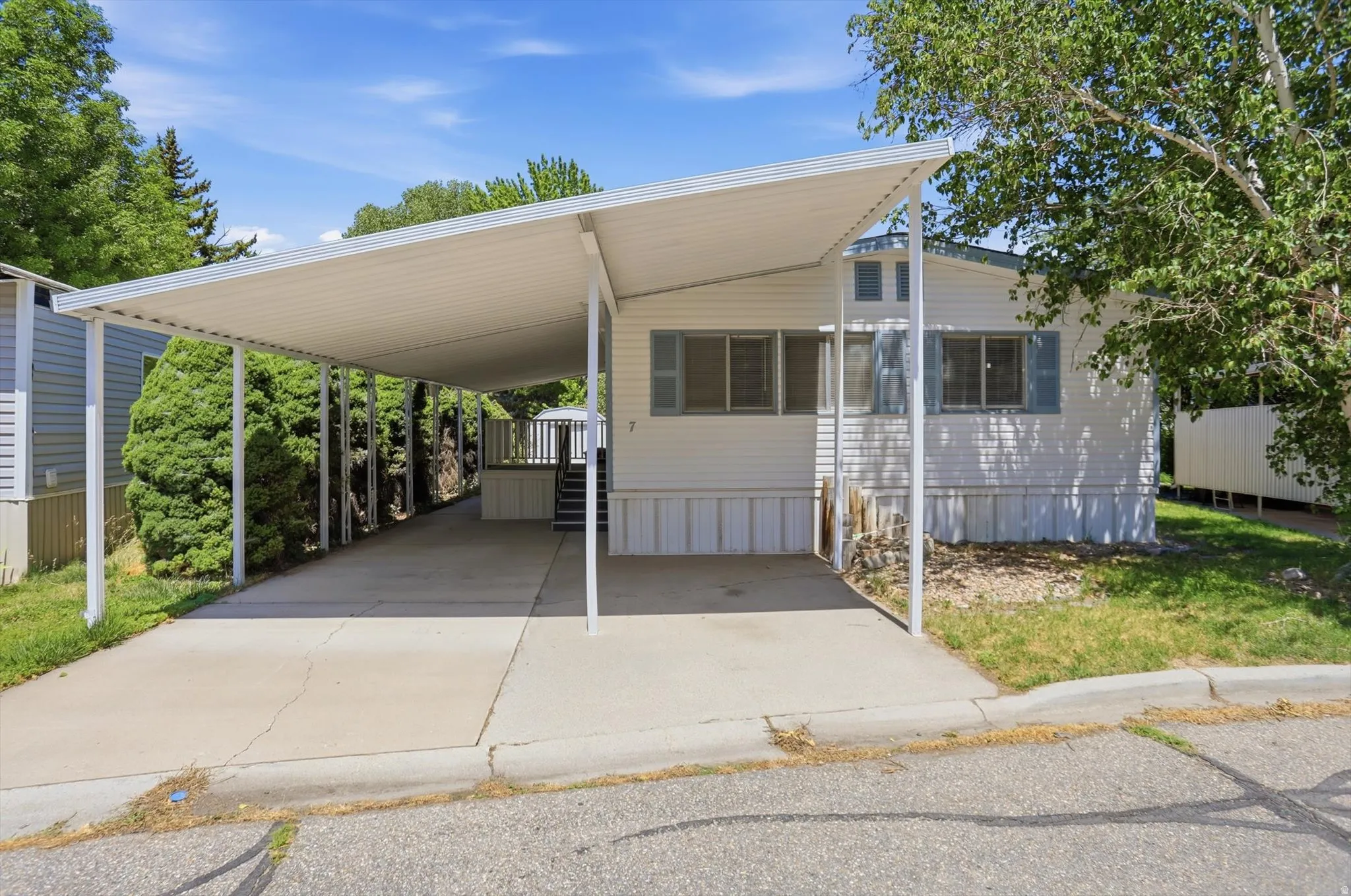 White siding exterior with a dedicated covered carport and concrete driveway