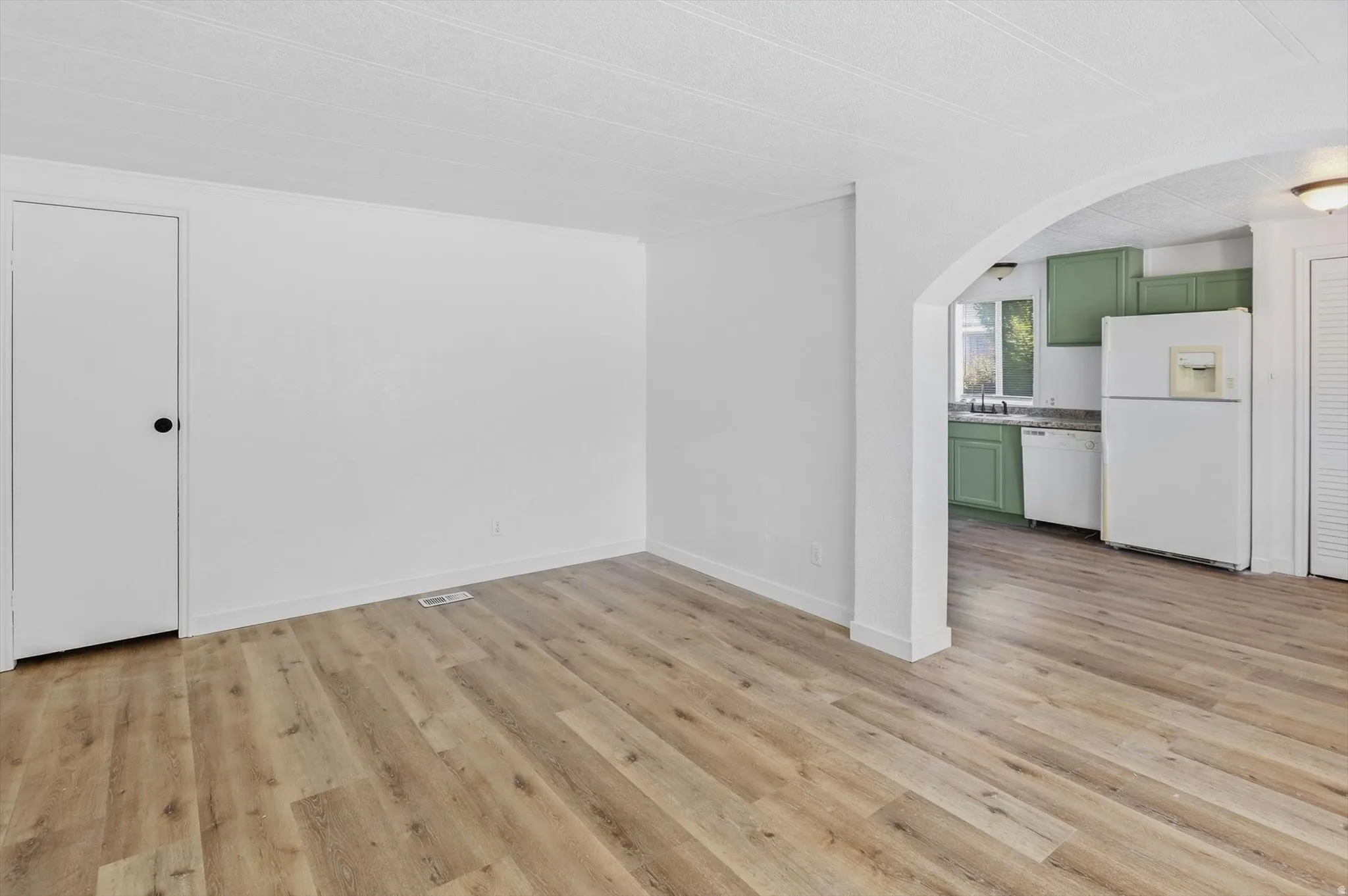 Bright interior space featuring wood-finish flooring, white walls, and a recessed air vent